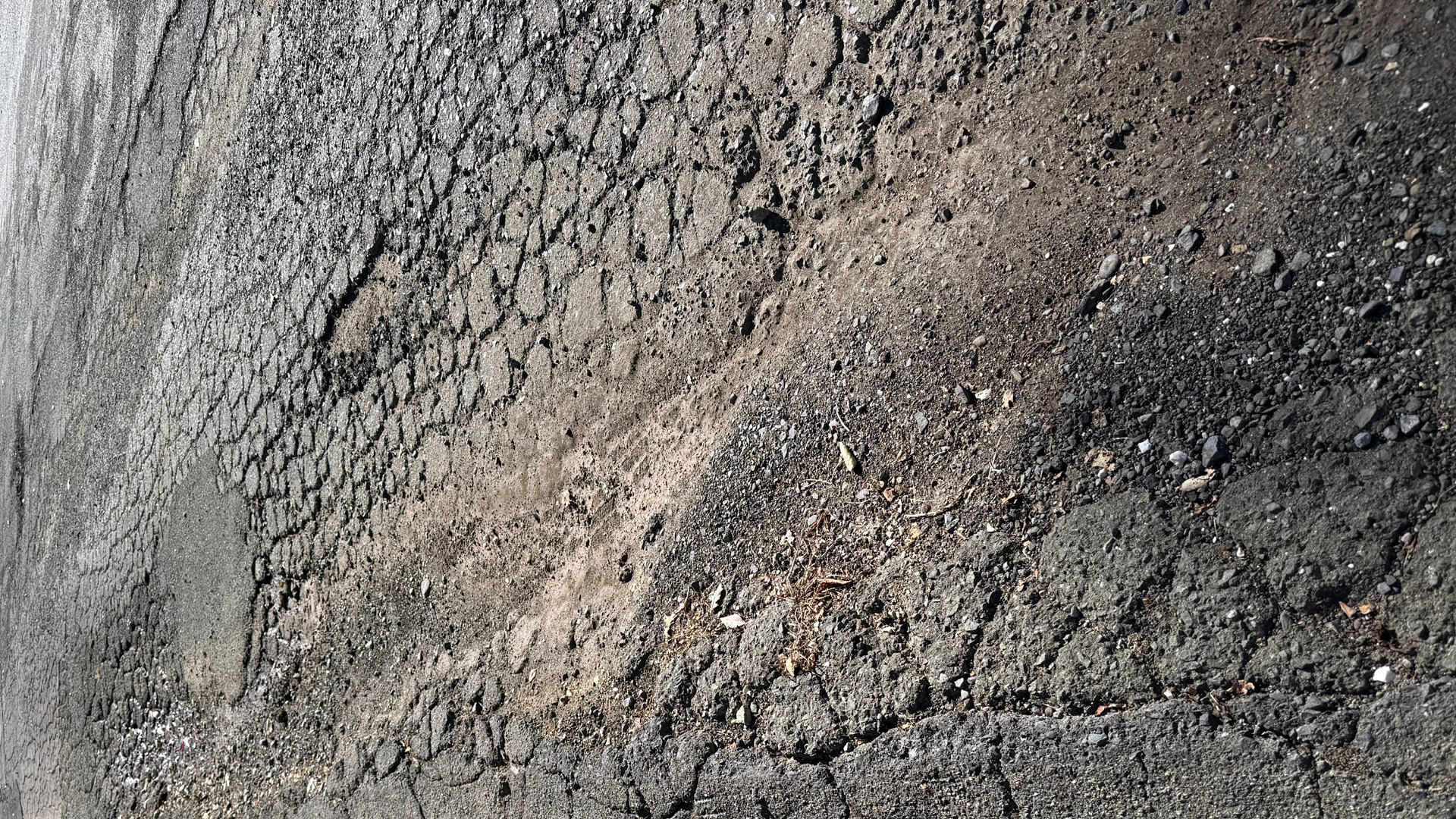 Maplewood Drive in Rancho Madrone on October 24, 2026, showing severe alligator cracking and crumbling asphalt with loose gravel.